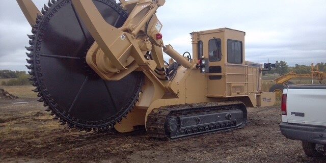 Large tracked trenching machine with circular cutting wheel used for underground utility installation