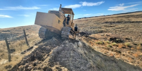 Tracked construction equipment navigating uneven terrain during rural site preparation